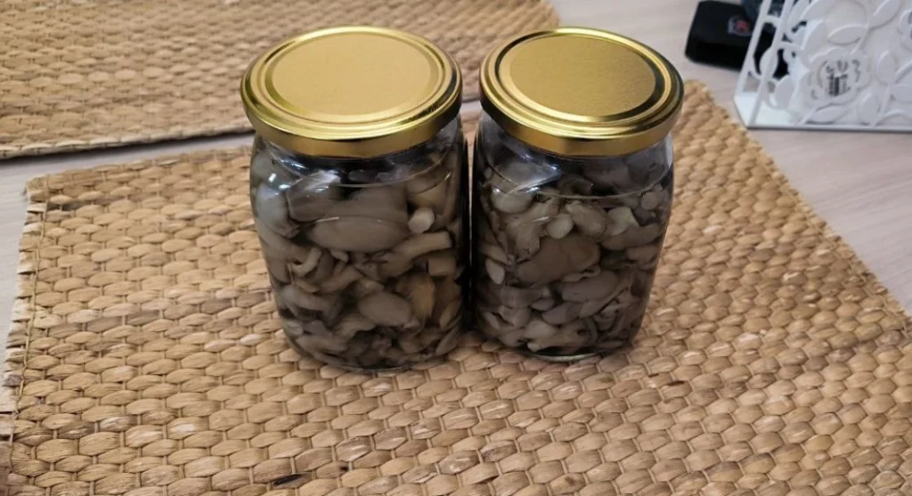 Стеклянные банки с маринованной вешенкой, чесноком и специями